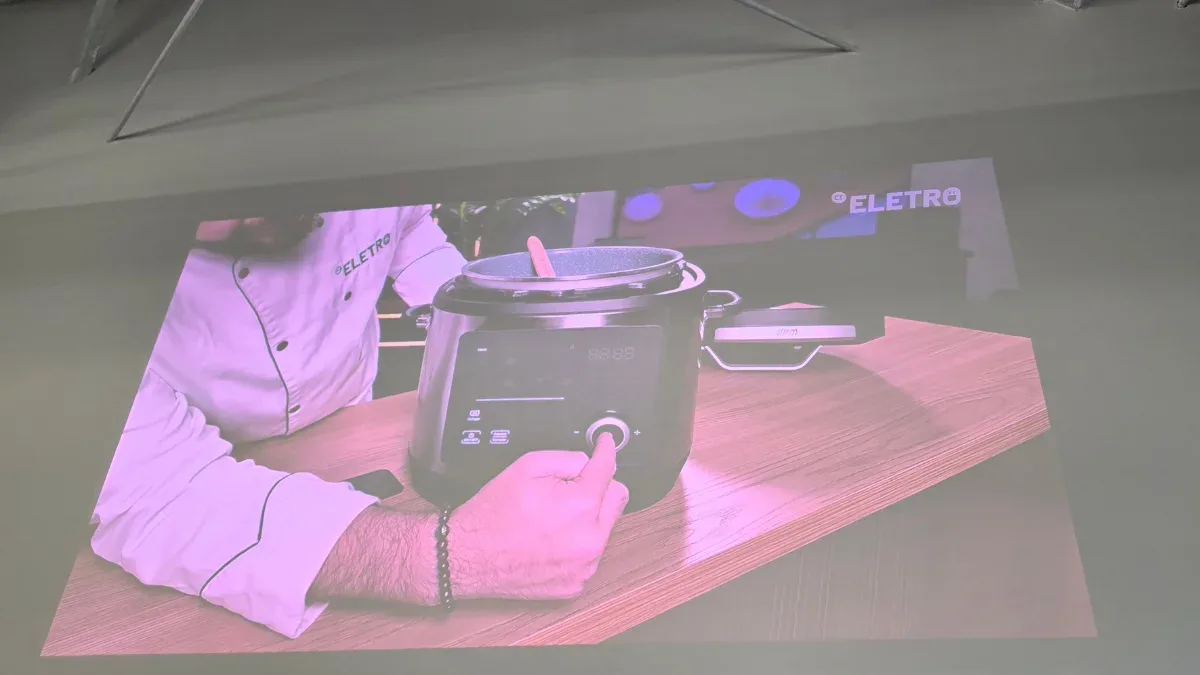 Projetor 4K posicionado sobre mesa exibindo projeção em sala iluminada por janelas