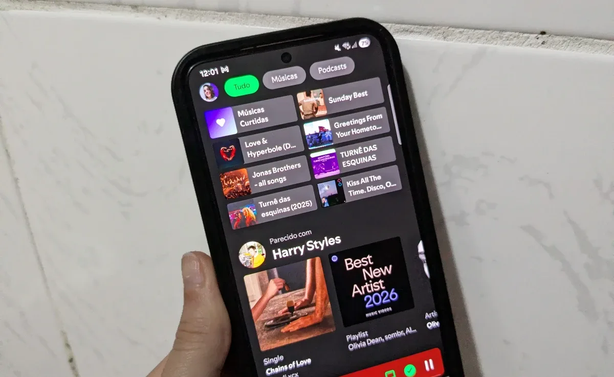 Smartphone apoiado sobre mesa de madeira exibindo aplicativo do Spotify aberto